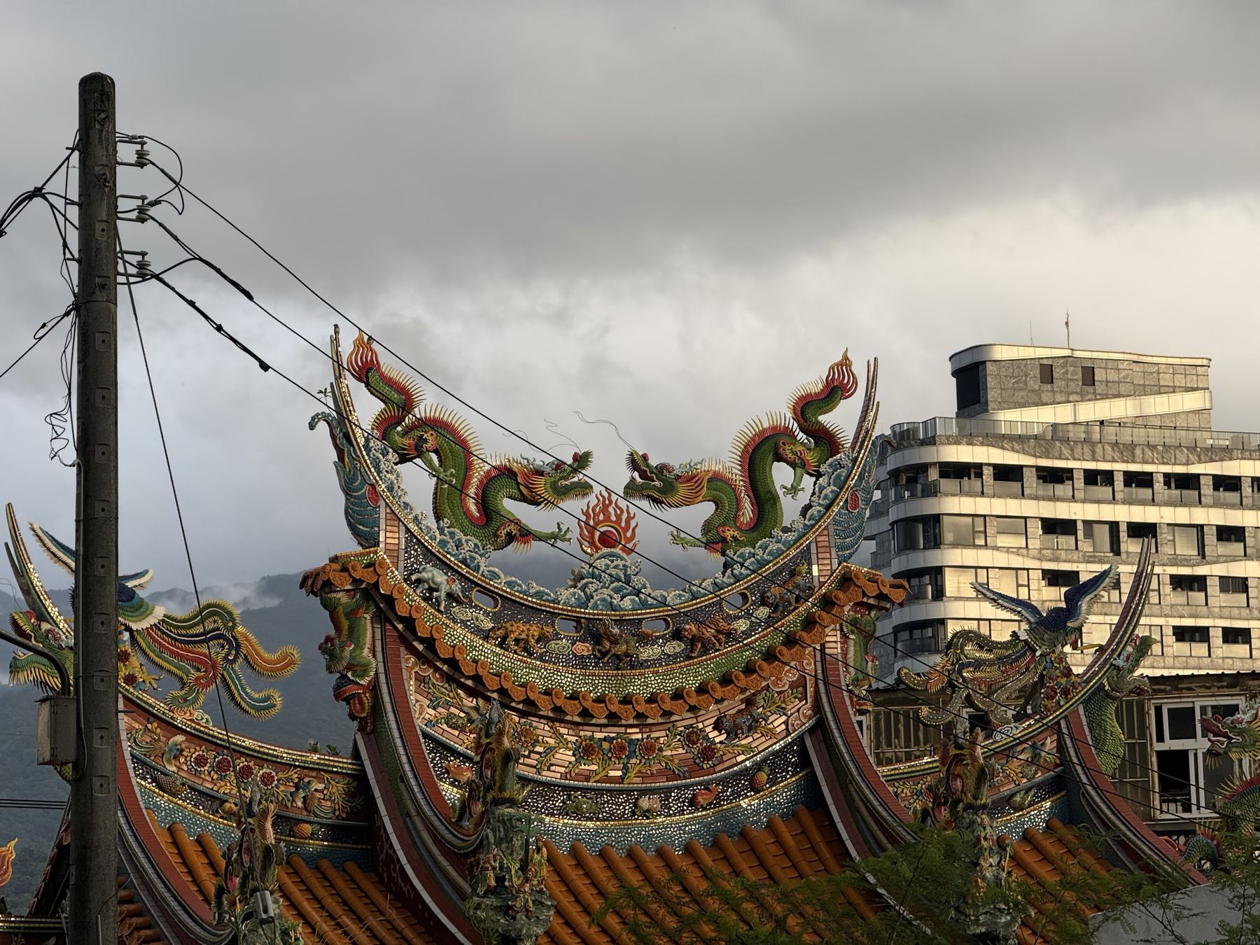 Dragons on an ornate temple roof under storm clouds